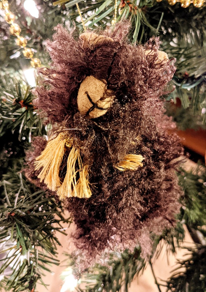 a brown, very fuzzy llama wears yellow tassels and just looks frazzled